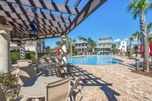 a patio with a table and chairs next to a swimming pool at The Village Blue Haven Condo - Private Beach Access Pool & Hot Tub in Rosemary Beach
