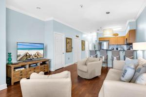 a living room with white furniture and a flat screen tv at The Village Blue Haven Condo - Private Beach Access Pool & Hot Tub in Rosemary Beach +33 photos