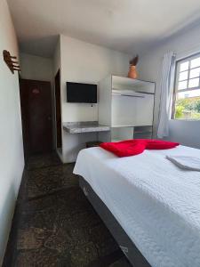 a bedroom with a large white bed with red pillows at Hotel Montanhas de Minas in Diamantina