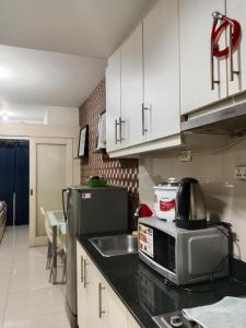 a kitchen with white cabinets and a sink and a microwave at Sea Residence Tower EF Lets in Manila