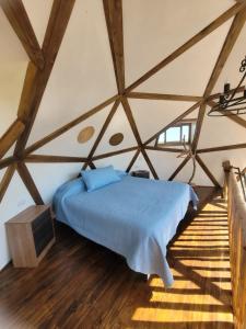 a bedroom with a bed in a room with wooden floors at Domo Tunquen in Tunquén