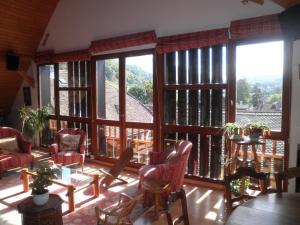 ein Wohnzimmer mit großen Fenstern sowie einem Tisch und Stühlen in der Unterkunft La grange in Menthon-Saint-Bernard