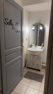 a bathroom with a sink and a door with a mirror at Studio meublé in Mulhouse