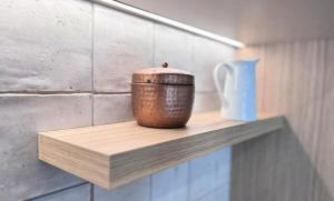 a pot sitting on a wooden shelf with a vase at Central City Queenstown Retreat - 3 Bedroom Apartment in Queenstown +4 photos