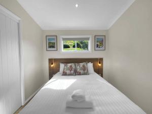 a white bedroom with a bed with a window at Bimbadeen Estate Villa 1 in Mount View