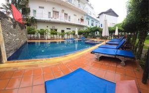 a large swimming pool with blue benches in front of a building at Blossoming Romduol Boutique in Siem Reap