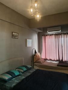 a room with two beds and a window with pink curtains at Oceanwhite Homestay Corus in Port Dickson