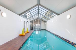 an indoor swimming pool with a glass ceiling at Handy CBD Covered Free Parking Gym 2 Bdrm in Christchurch