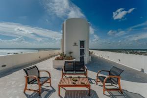 a patio with two chairs and a table on the beach at Departamento con espectaculares vistas al mar in Telchac Puerto