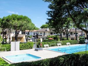 a swimming pool with trees and houses in the background at Charming villa in Porto Santa Margherita with private garden in Porto Santa Margherita di Caorle