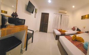 a room with two beds and a living room with a tv at Blossoming Romduol Boutique in Siem Reap