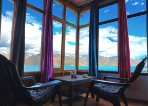 a room with a table and chairs and a large window at pangong rainbow cottage in Lukung +41 photos