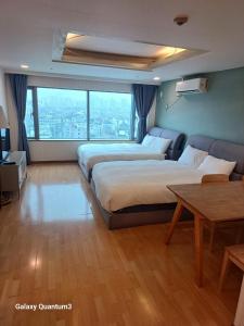首尔Hongdae Guesthouse4 - 1min from Hongik Uni station Exit #1的有两张床和一张桌子的酒店房间