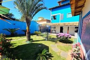 a yard with a blue building and a palm tree at Gran casa, Chalet, con Piscina en Búzios in Buzios