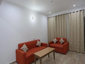 a living room with two red chairs and a table at Super Hotel O Summer King in Nainital