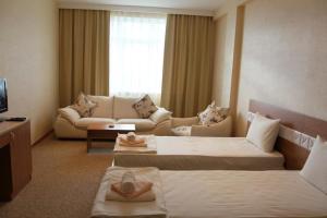 a hotel room with two beds and a couch at Gabala Tufandag City Hotel in Gabala