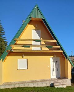 une maison jaune avec un toit vert dans l'établissement D&N place, à Žabljak