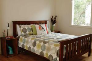 a bedroom with a bed with a wooden frame and a window at Driftwood in Venus Bay