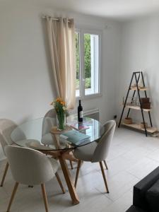 a dining room with a glass table and chairs at Charmante villa à istres in Istres