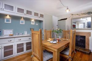 a dining room with a wooden table and a kitchen at Friday Cottage - Brixham in Brixham