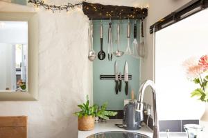 a kitchen with utensils hanging from a wall at Friday Cottage - Brixham in Brixham +32 photos