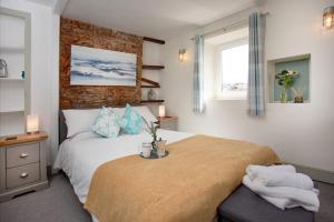 a bedroom with a bed and a brick wall at Friday Cottage - Brixham in Brixham