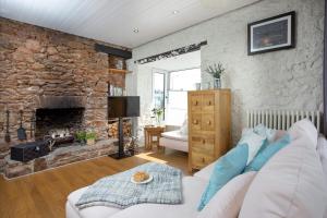 a living room with a couch and a stone fireplace at Friday Cottage - Brixham in Brixham