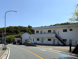 Una calle vacía al lado de un edificio blanco con una escalera en 伊勢志摩観光に最適 パールロードの玄関口 PAARU inn 2階B室 セルフチェックイン, en Toba