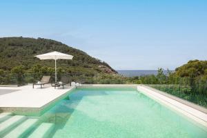 サン・ジョセップ・デ・サ・タライアにあるVilla Sargantanaのパラソルと椅子付きのスイミングプール