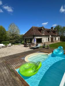 a swimming pool with a green inflatable toy in front of a house at Longère normande avec piscine et jardin in Landepéreuse