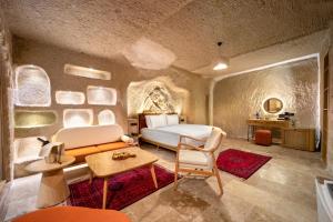 a bedroom with a bed and a couch and a table at Zafora Cave Suites Hotel Cappadocia in Uçhisar