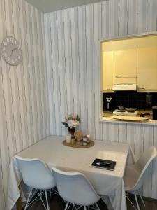 a dining room table with white chairs and a clock at Kaksio Pieksämäen keskustassa in Pieksamaki +5 photos