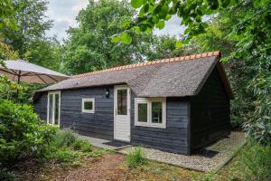 einen kleinen schwarzen Schuppen mit weißer Tür in der Unterkunft Heivlinder Comfort 4p in Ermelo