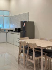 a kitchen with a wooden table with chairs and a refrigerator at De Home Kluang Homestay in Kluang