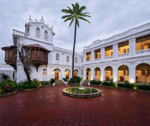 a large white building with a palm tree in the middle at juSTa Diwans Bungalow in Ahmedabad