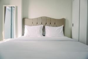 a bed with white sheets and pillows and a window at Pleasurable and Tidy Studio Daan Mogot City Apartment By Travelio in Jakarta