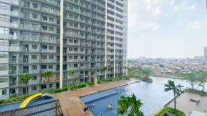a large building with a swimming pool next to a river at Pleasurable and Tidy Studio Daan Mogot City Apartment By Travelio in Jakarta