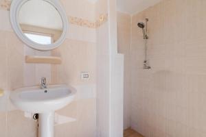 a white bathroom with a sink and a mirror at Fronte Mare Villa Raffaele in Punta Prosciutto +21 photos
