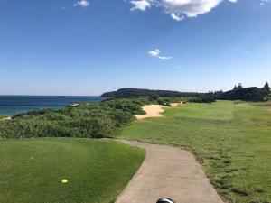 Un campo de golf con un sendero y el océano. en Luxury 3 bedroom townhouse, stroll to beaches, en Shelly Beach