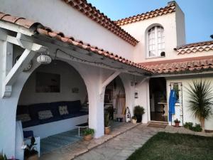 a house with a porch with a blue couch at La paillote des Ninous in Bassan