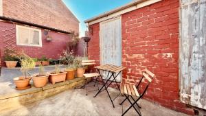 un patio con mesa y sillas junto a una pared de ladrillo en Chatsworth Terrace - Chesterfield Centre and Peak District, en Chesterfield