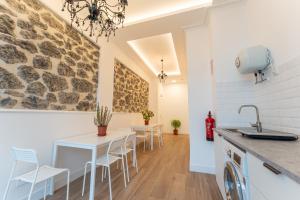 a kitchen with a table and chairs and a stone wall at La bahia rooms in Santander
