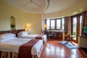 a hotel room with two beds and a desk at Arusha Serena Hotel in Tengeru