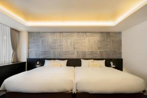 a bedroom with two beds with white sheets at Homm Stay Nagi Sanjo Kyoto By Banyan Group in Kyoto