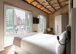 a bedroom with a large bed and a large window at Limehome Valencia de Xativa in Valencia