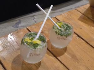 two cocktails with straws on a wooden table at Bonjour Travellers Hostel in Hyderabad