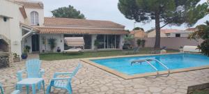 a swimming pool with blue chairs and a table at La paillote des Ninous in Bassan