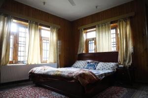 a bedroom with a bed in a room with windows at The Bilt farmhouse in Srinagar