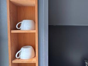 a wooden shelf with two white mugs on it at seeglueck HÄUSLE - Charmantes Ferienhaus mit Innenhof in zentraler Altstadtlage von Konstanz in Konstanz +35 photos