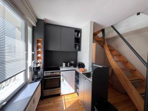 a small kitchen with black cabinets and a staircase at seeglueck HÄUSLE - Charmantes Ferienhaus mit Innenhof in zentraler Altstadtlage von Konstanz in Konstanz +35 photos
